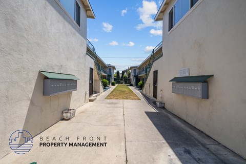 an empty alleyway between two buildings with green bins on the side of the street