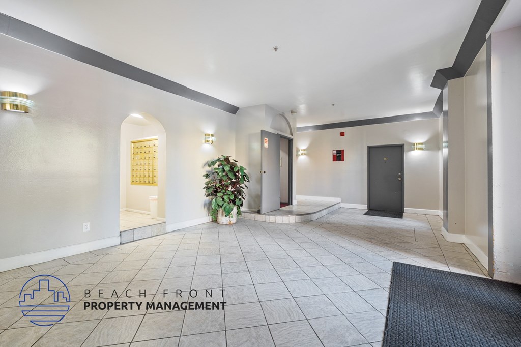 A hallway with a plant in the middle and a sign that says "BEACH FRONT PROPERTY MANAGEMENT".