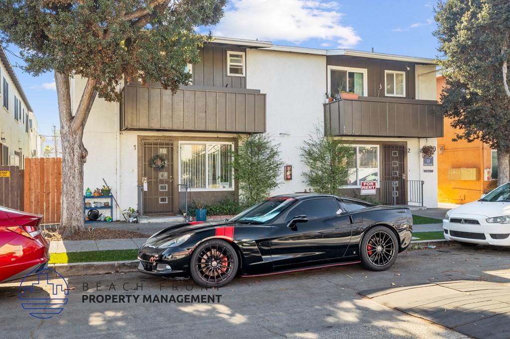 A black sports car is parked in front of a two-story building.