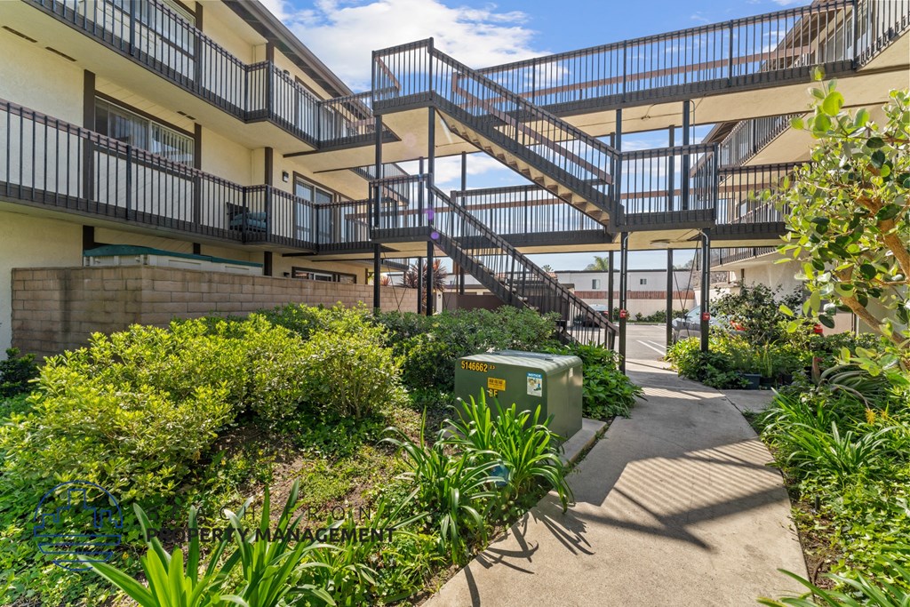 A green container is on the ground next to a concrete path.