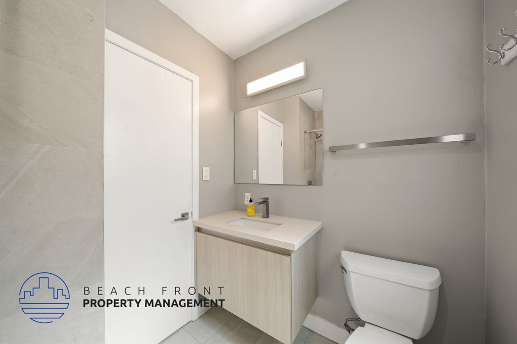 A bathroom with a toilet, sink, and mirror.