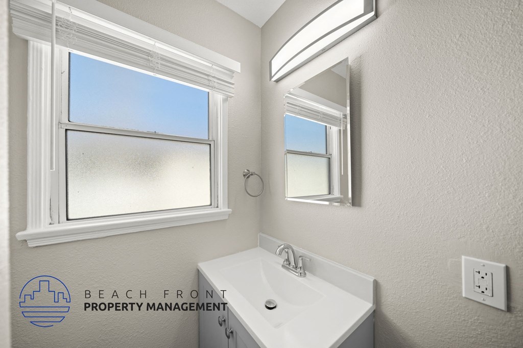 A bathroom with a large window and a white sink.