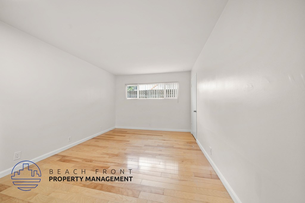 A room with wooden flooring and a window with blinds.