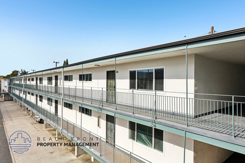 A row of white buildings with balconies and the logo of Beachfront Property Management in the bottom left corner.