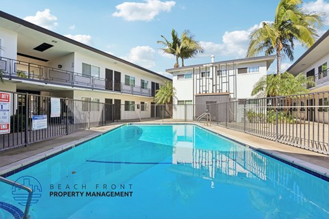 A swimming pool in front of a building with the words Beach Front Property Management.