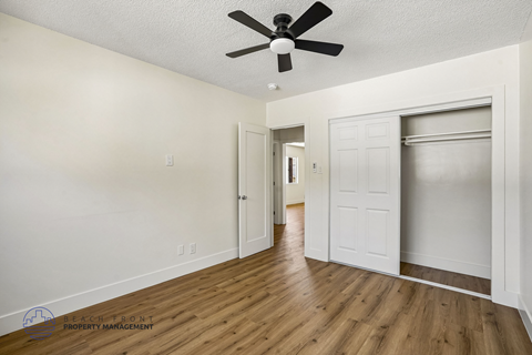 A spacious room with a ceiling fan and wooden flooring.