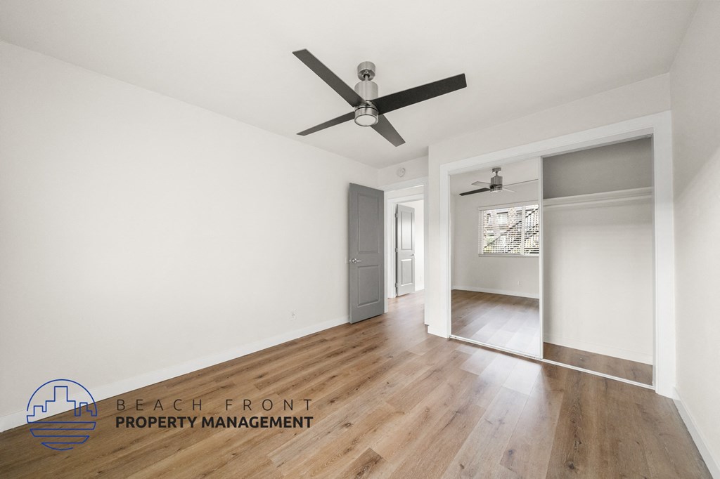 A room with a ceiling fan and wooden flooring.