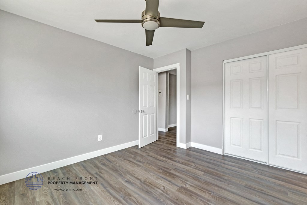 the living room of a house with grey walls and a ceiling fan