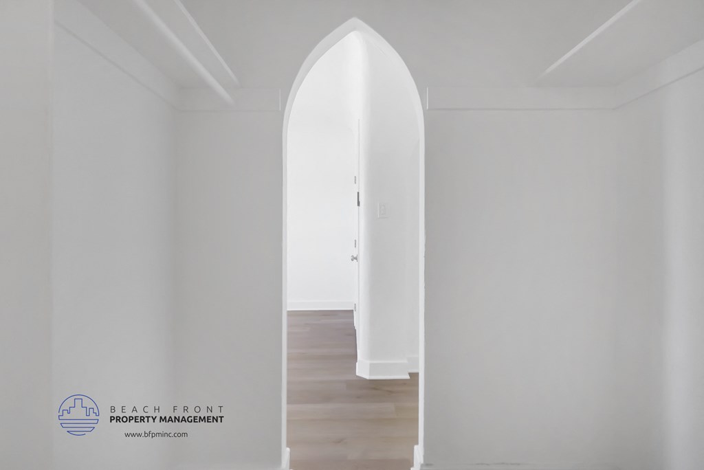an arched doorway in a white room with wood flooring and a white door