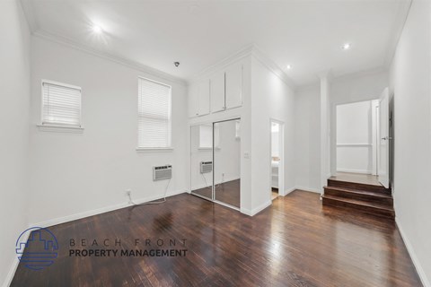 a living room with hardwood floors and white walls and a mirrored door