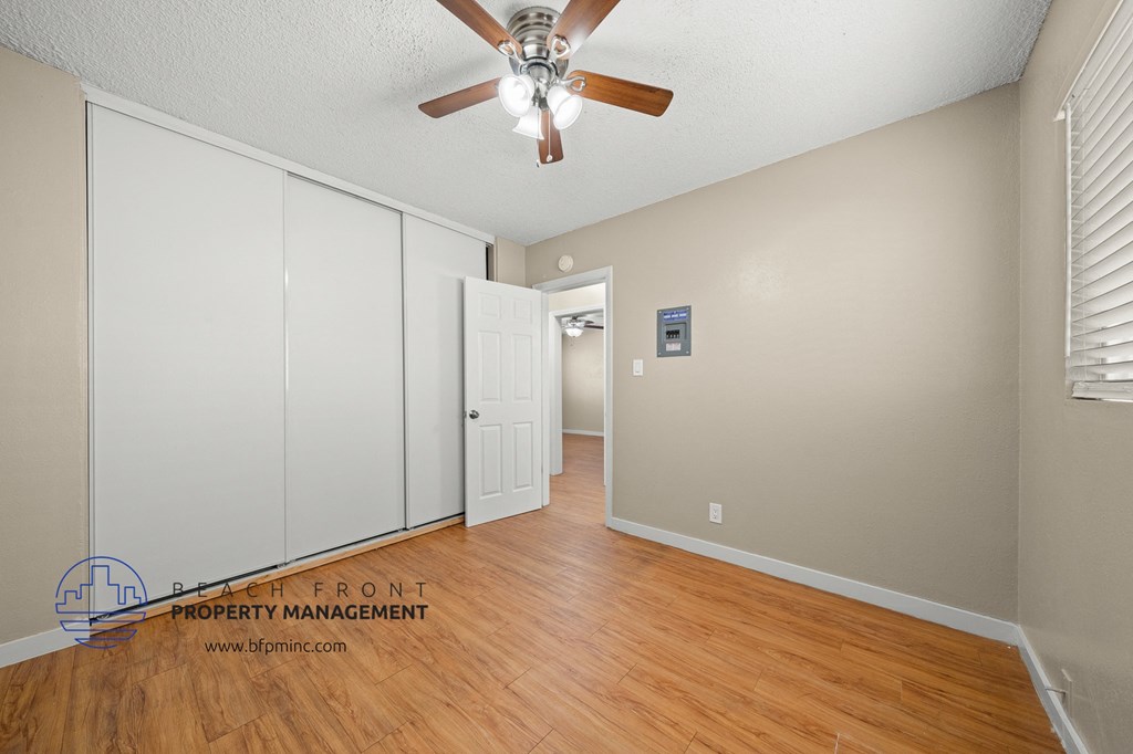 the living room and dining room with wood flooring and a ceiling fan