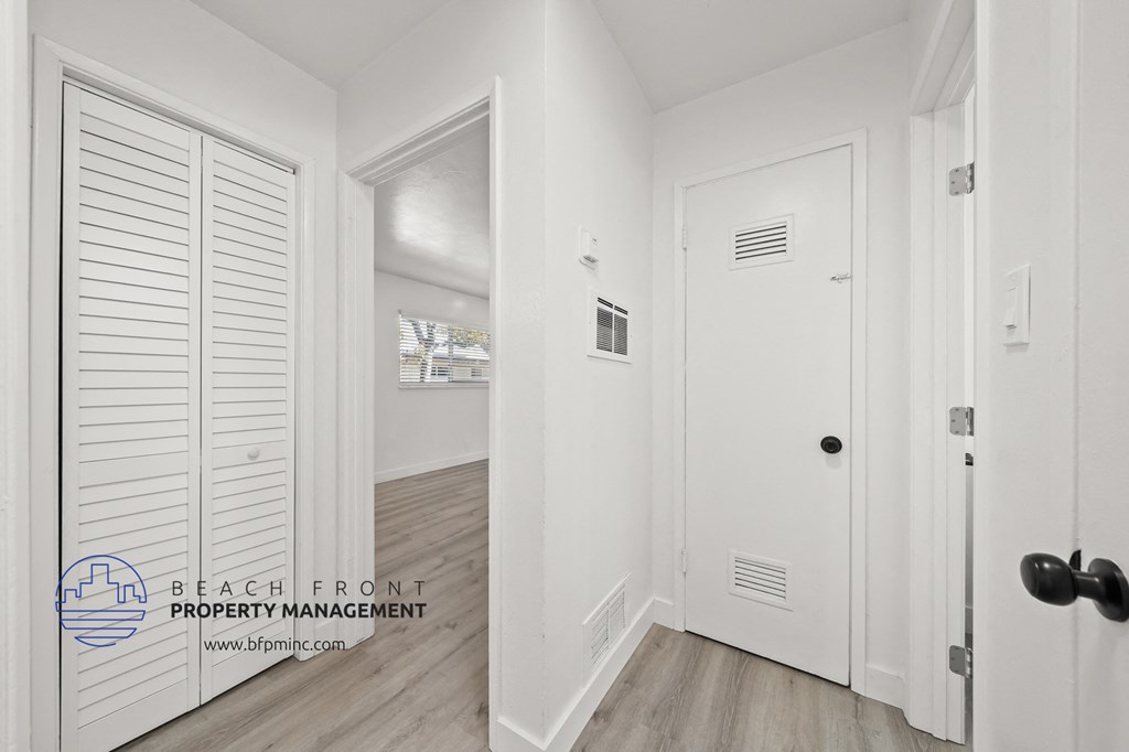 a small hallway with white walls and hardwood floors