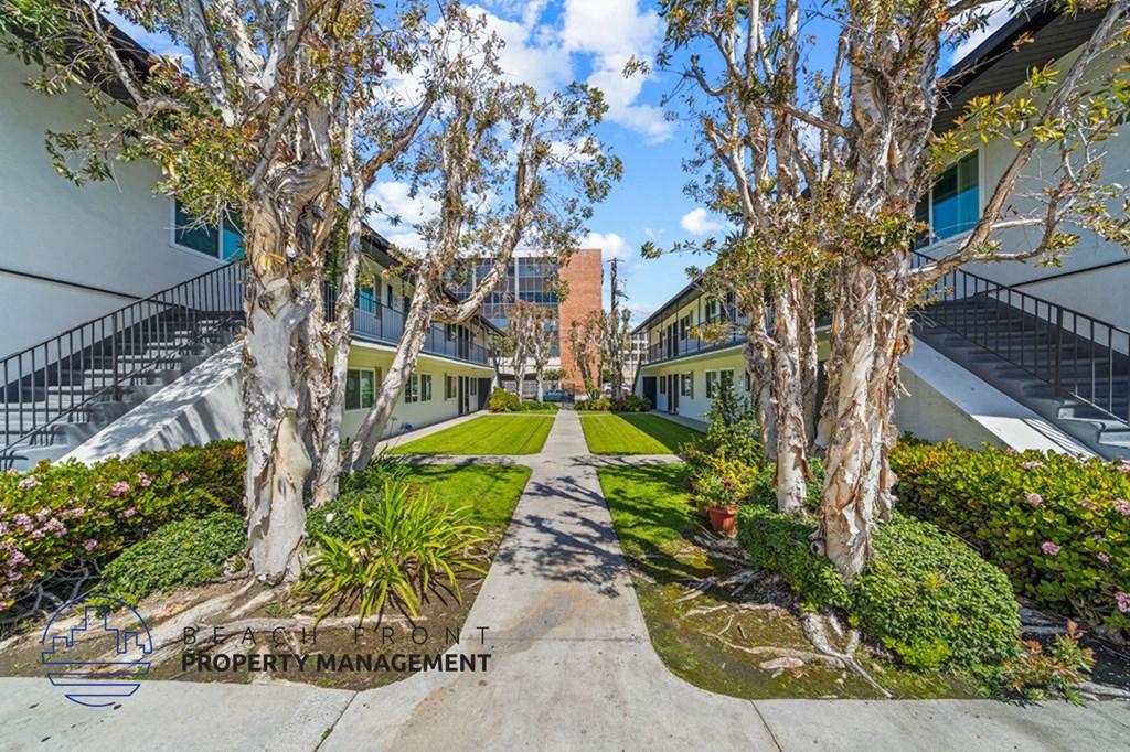 a courtyard between two buildings with trees and grass