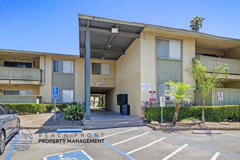 a beige apartment building with a parking lot and palm trees