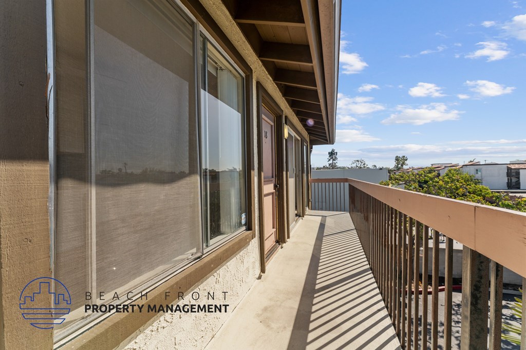 A balcony with a view of the beach and buildings in the distance.