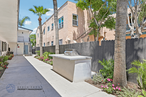 A concrete planter sits in the middle of a walkway between two buildings.