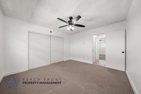 A spacious room with a ceiling fan and carpeted floor.