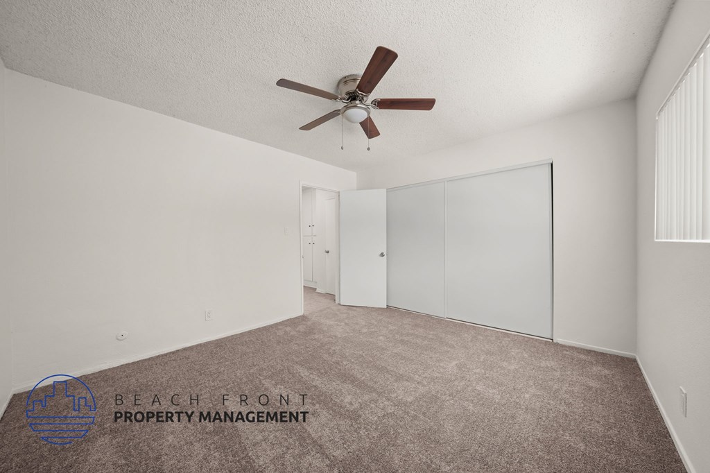 A room with a ceiling fan and carpeted floor.