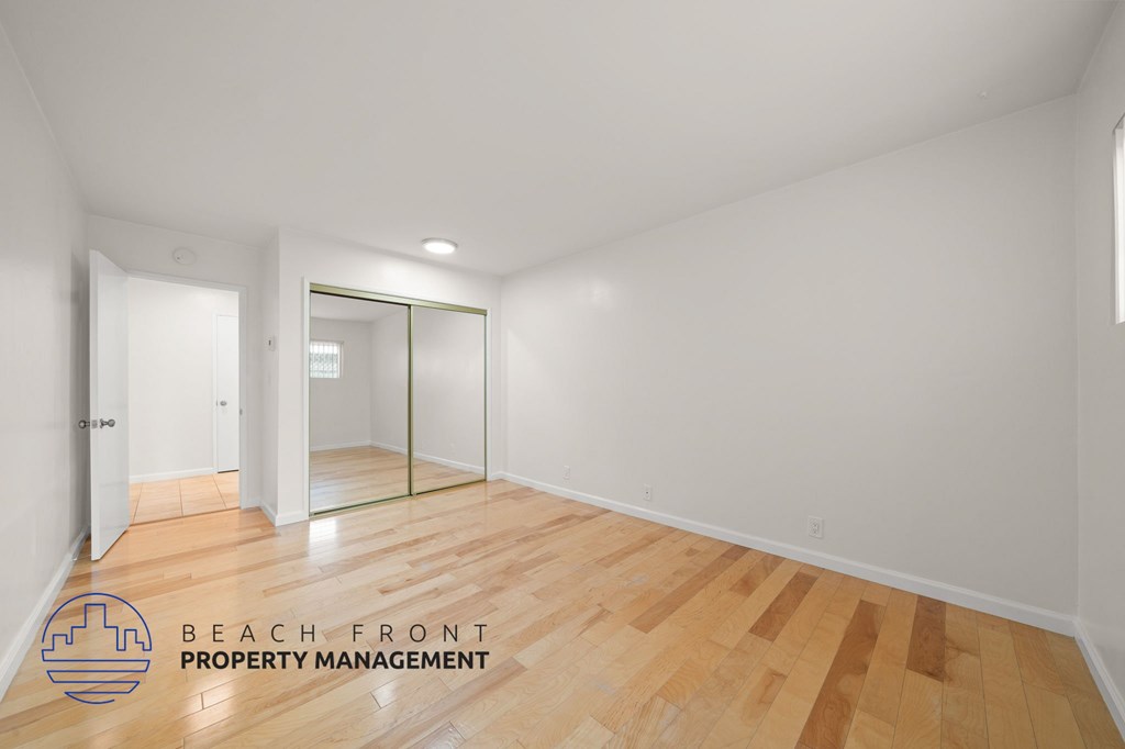 A room with wooden flooring and a mirror on the wall.