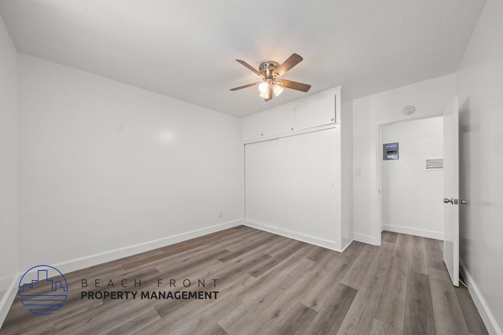 A spacious room with a ceiling fan and wooden flooring.