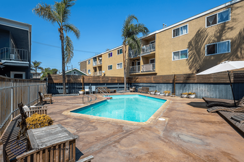 A pool surrounded by a patio and apartment buildings.