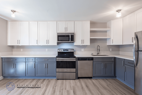 A kitchen with white cabinets and a wooden floor.