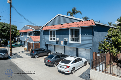 A blue house with a red roof and a sign that says Beach Front Property Management.