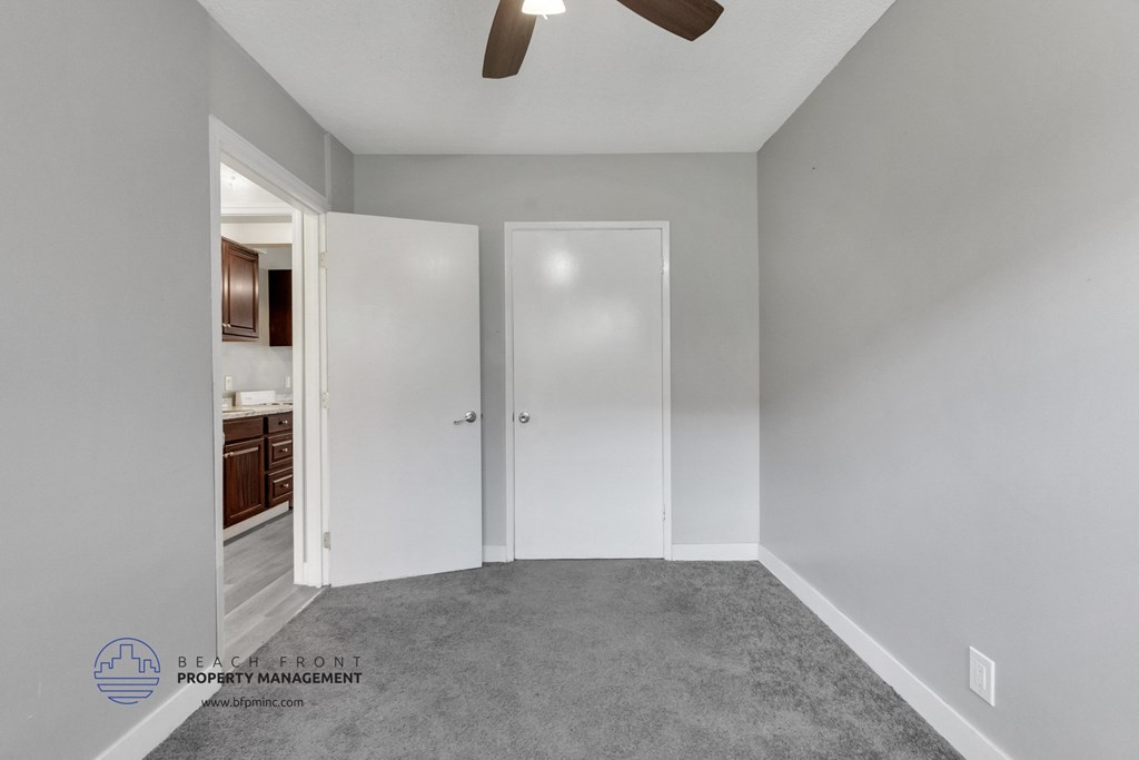 a bedroom with gray carpet and a ceiling fan