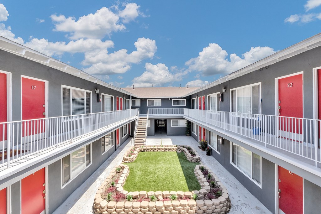 a courtyard with green grass and red doors