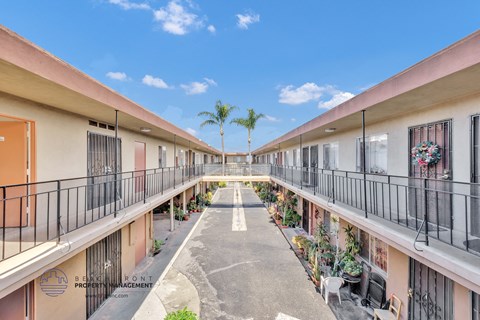 a courtyard between two buildings with balconies and plants