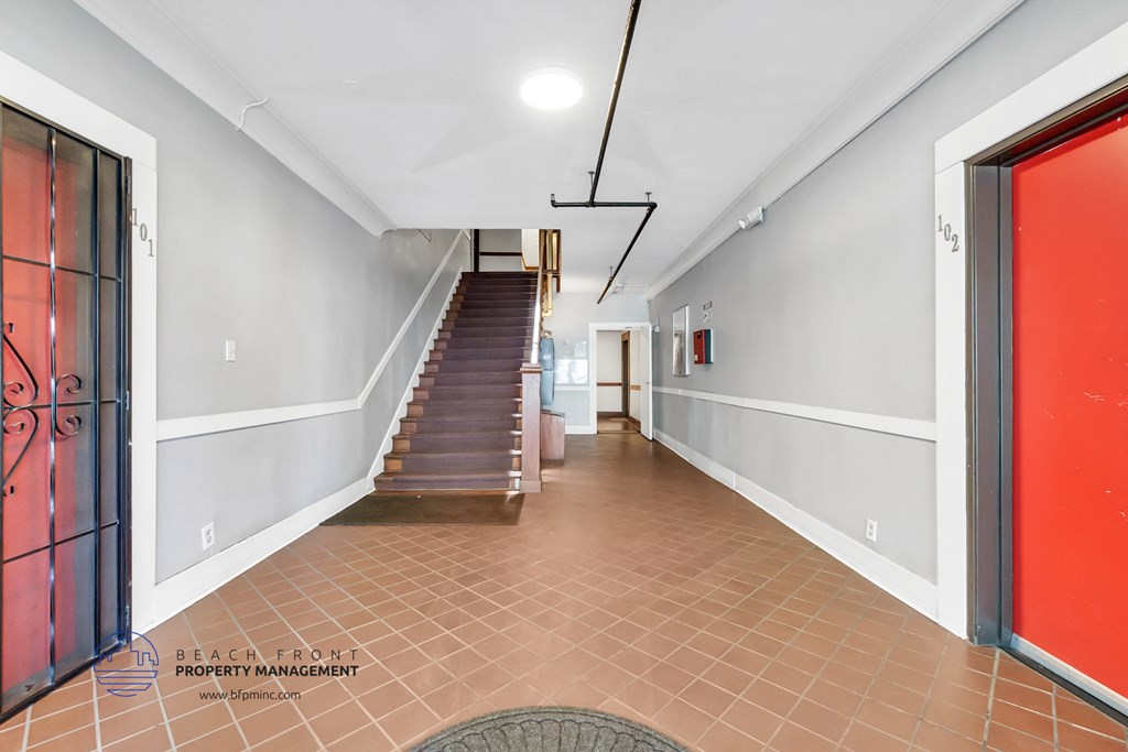 a long hallway with a staircase and doors and a red door