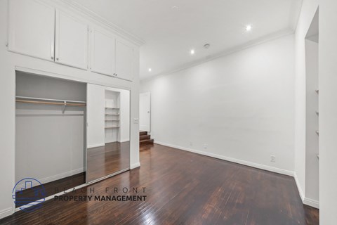 a living room with white walls and wood floors and a closet
