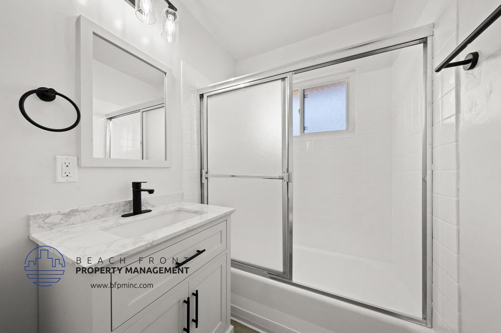 a bathroom with a white sink and a shower with a glass door