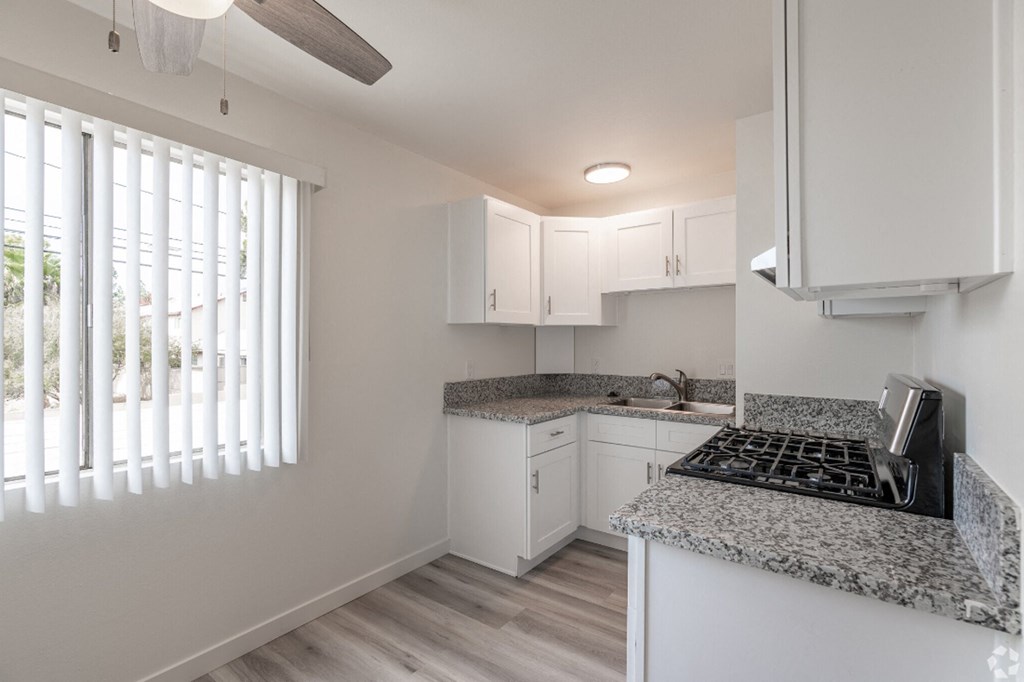 an empty kitchen with white cabinets and granite counter tops