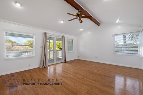 A spacious room with wooden floors and a ceiling fan.