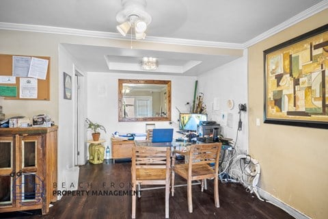 A room with a wooden table and chairs, a mirror, and a painting on the wall.