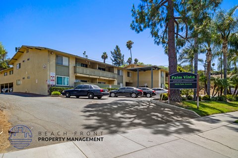 a beige apartment building with a parking lot and palm trees