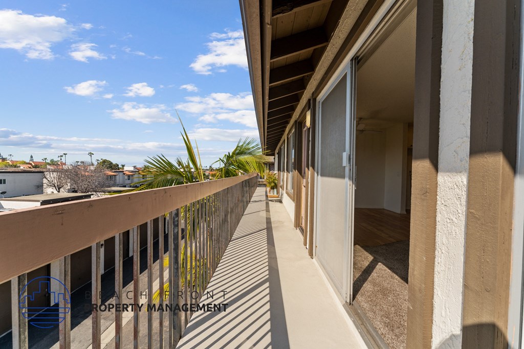 A balcony with a metal railing and a view of the sky and buildings.