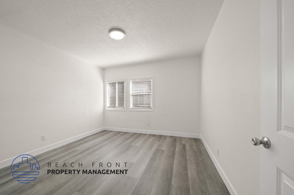 A room with a door, window, and a logo for Beach Front Property Management.