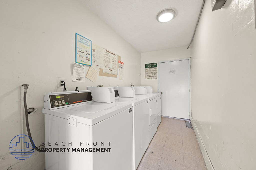 A laundry room with a washer and dryer, a sign on the wall and a door at the end of the room.