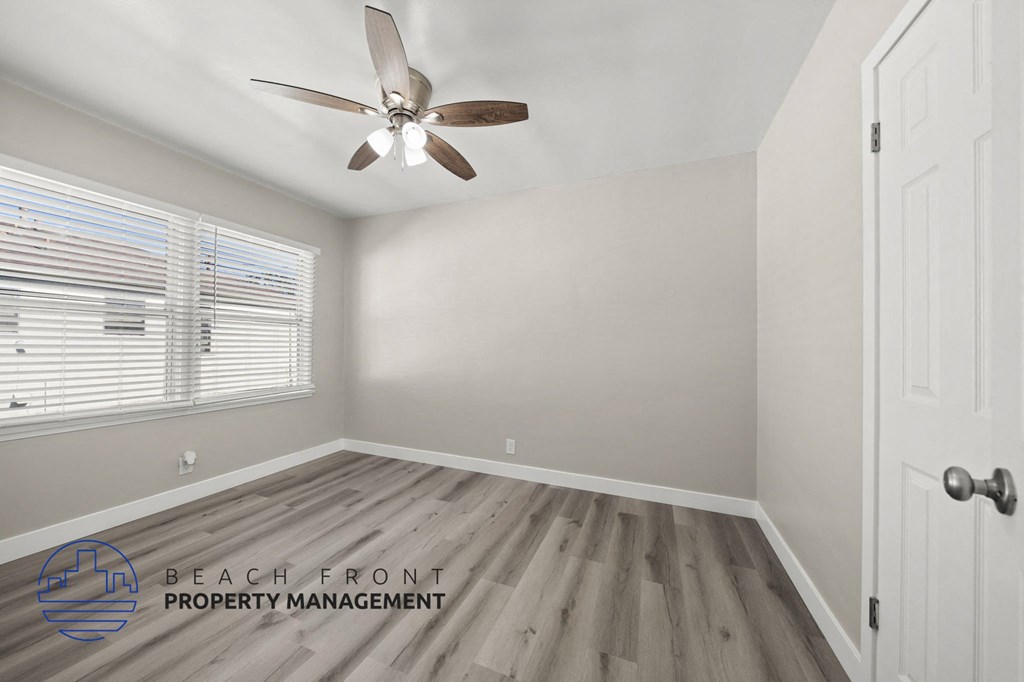 A room with a ceiling fan and wooden flooring.