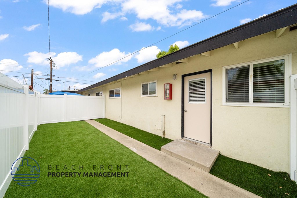 A white building with a green lawn in front.