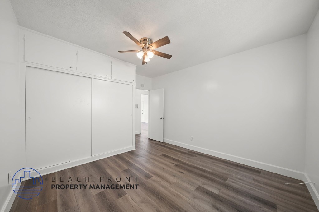 A room with a ceiling fan and wooden flooring.