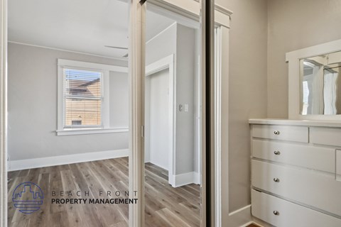 A white bedroom with a dresser and a mirror.