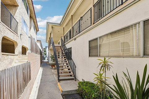 A narrow street with a wooden fence on the left and a white building on the right.