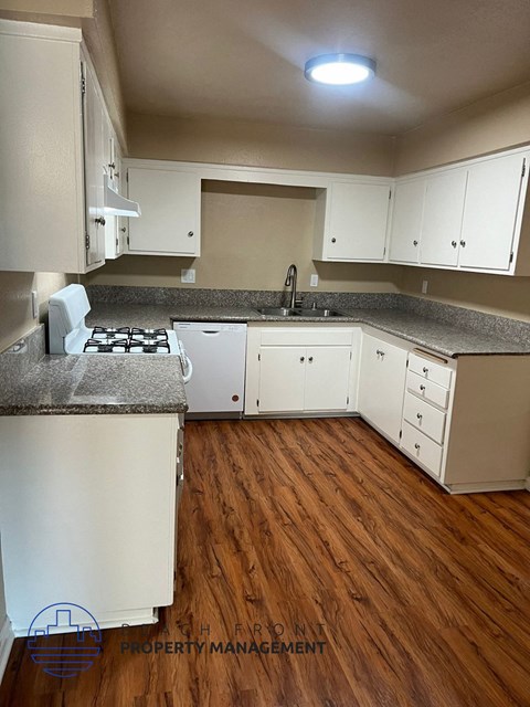 A kitchen with white cabinets and a wooden floor.