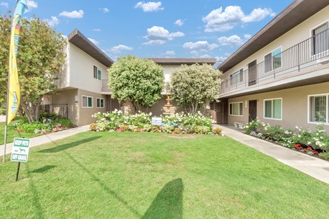 a yard in front of a building with grass and flowers
