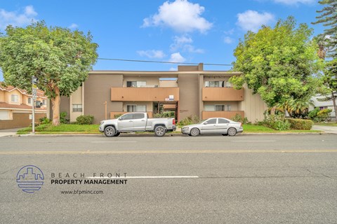 an apartment building with two cars parked in front of it