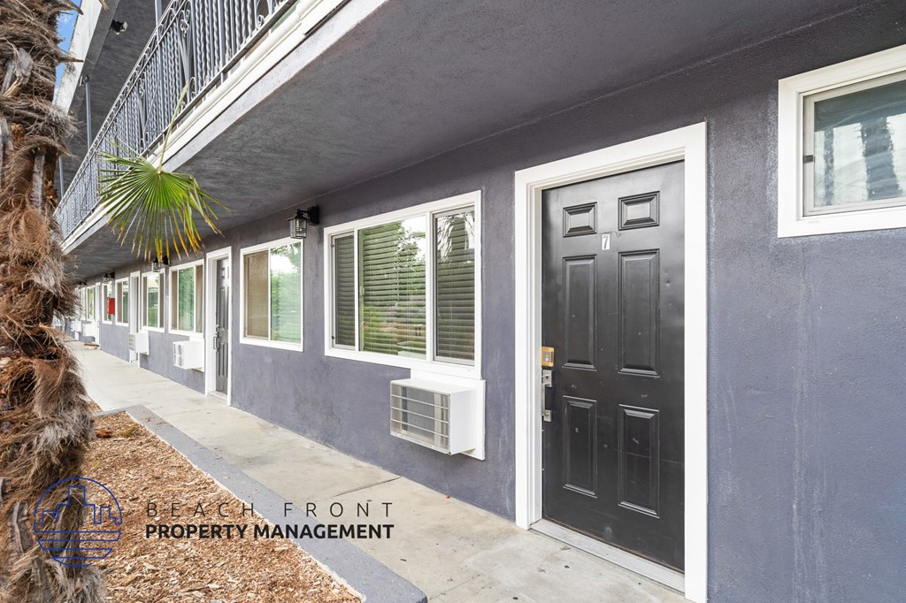 A building with a black door and windows with shutters.