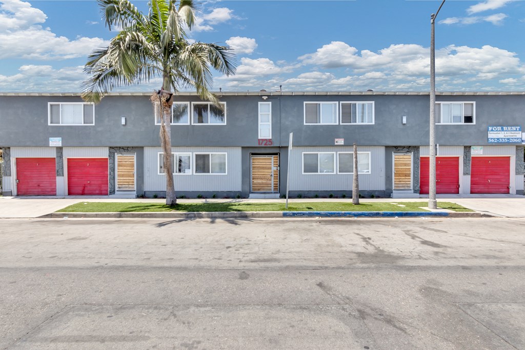 a building with three doors and a palm tree in front of it